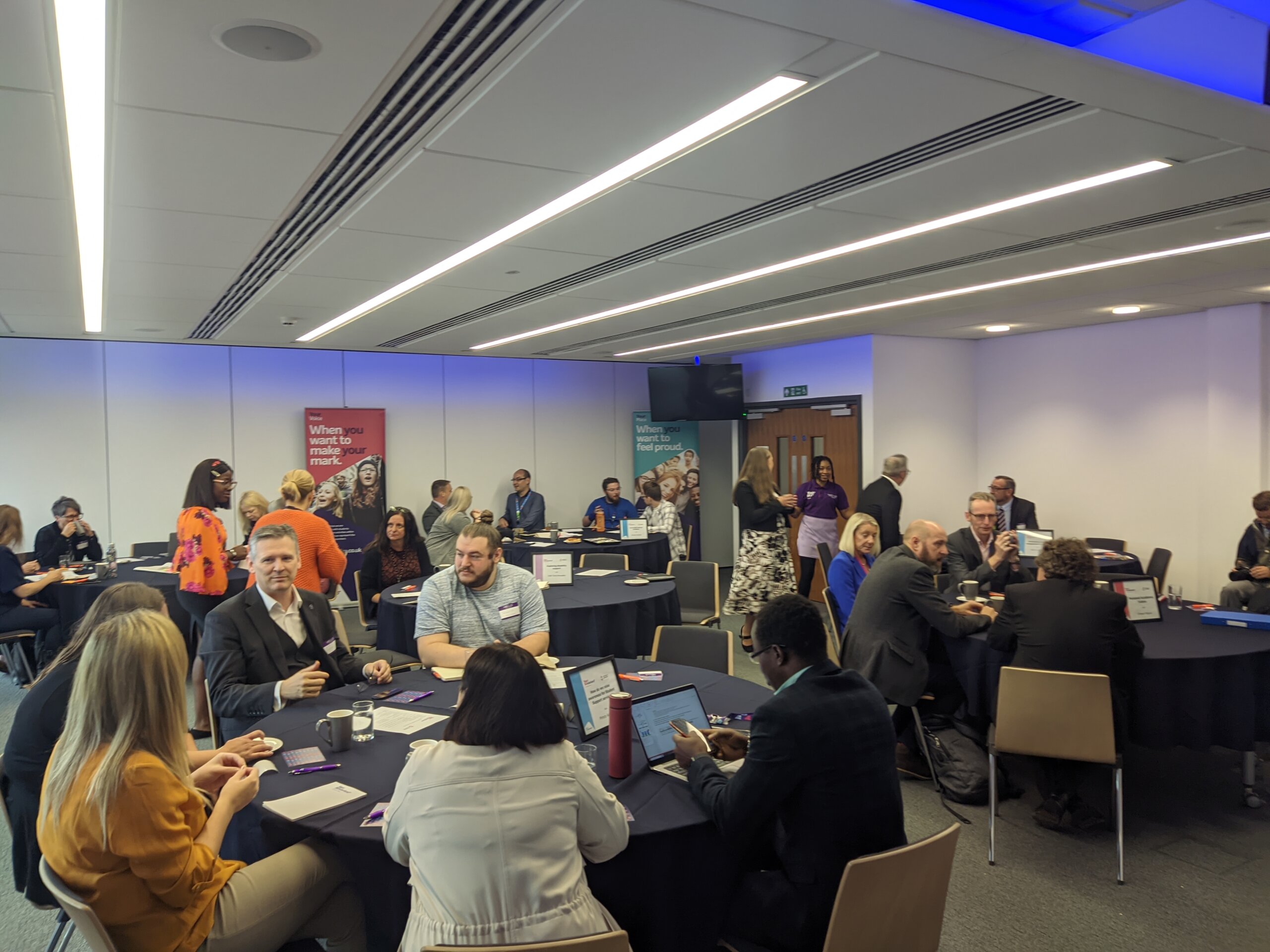 People are sitting and chatting in round tables in a formal business conference