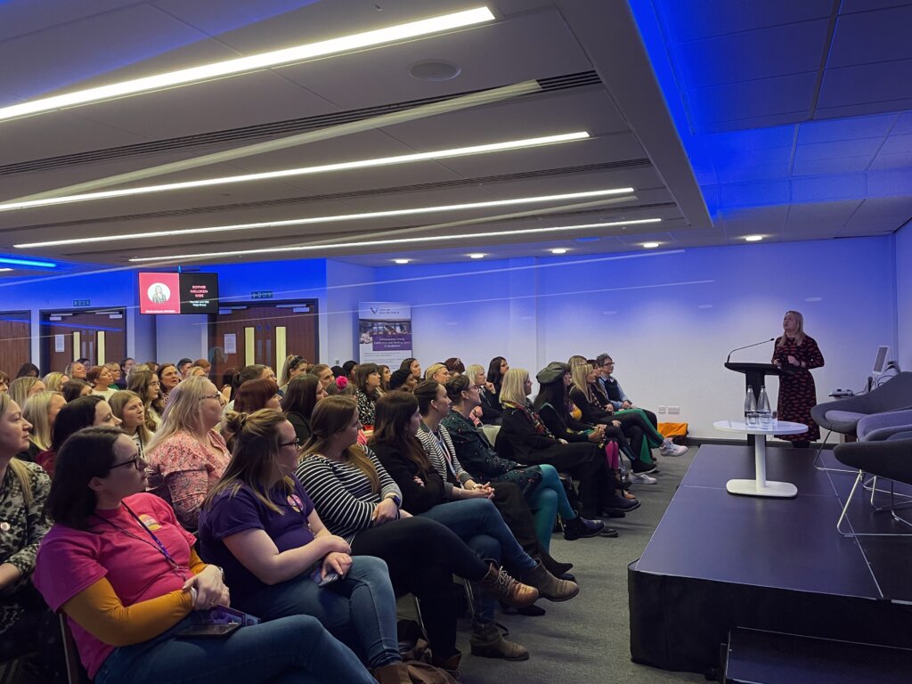 Guests sitting in a big conference room listening to the speaker on stage.